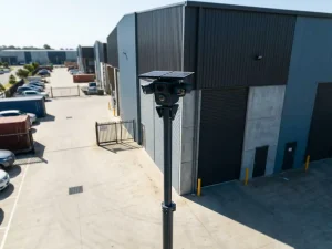 Professionele mobiele beveiligingscamera op telescopische paal bij moderne industriële faciliteit met betonnen binnenplaats