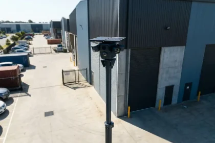 Professionele mobiele beveiligingscamera op telescopische paal bij moderne industriële faciliteit met betonnen binnenplaats